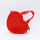 DIY Decoden customizable heart-shaped purse in cherry red with frosting-inspired glues, decorative sprinkles, and charms, featuring a detachable gold cross-body chain.